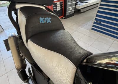 BMW K1300 : ajout de matelassage pour le confort du pilote, changement en selle bicolore et ajout de la broderie AC/DC dans les couleurs du logo de BMW
